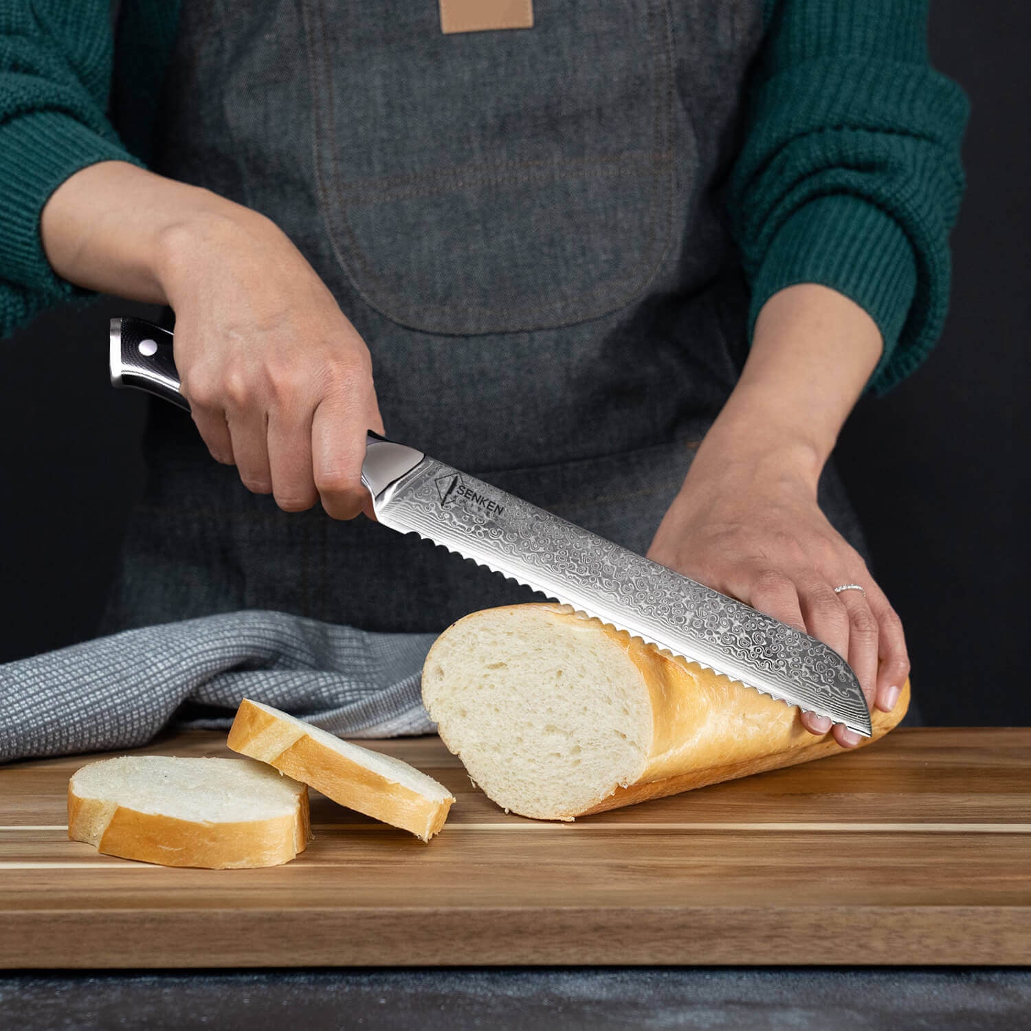 La mano del cuoco con un coltello affetta il pane su un tagliere da cucina