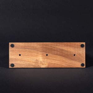 May include: The bottom of a wooden rectangular box with three holes and four black rubber feet.