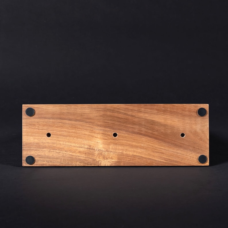 May include: The bottom of a wooden rectangular box with three holes and four black rubber feet.
