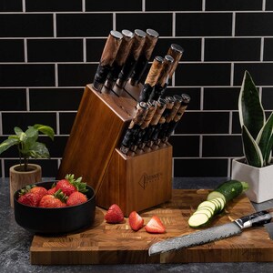 May include: A wooden knife block set with multiple knives, featuring brown and black handles. The set is displayed with a cutting board, strawberries, and sliced zucchini. The knives have a unique patterned blade design.