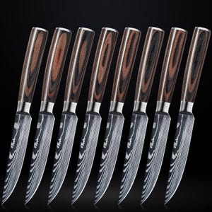 Pu&ograve; includere: Set di otto coltelli per bistecca in acciaio inossidabile con manici in legno. I coltelli hanno una lama ondulata in stile Damasco e un manico in legno nero e marrone.