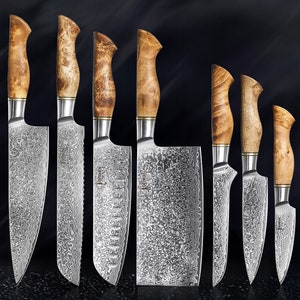 Può includere: Un set di otto coltelli da cucina con manici in legno e lama in acciaio damascato. I coltelli sono disposti in fila su uno sfondo nero.