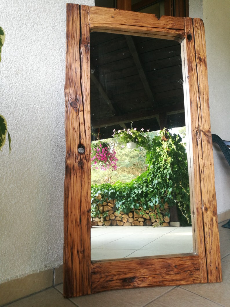 Puede incluir: Un espejo de madera r&uacute;stico con un marco rectangular. El marco est&aacute; hecho de madera recuperada con un acabado marr&oacute;n natural. El espejo refleja una vista de un jard&iacute;n con plantas verdes y flores.