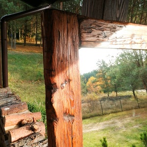 Puede incluir: Un espejo de madera r&uacute;stico con un acabado de madera natural. El espejo est&aacute; enmarcado con gruesas tablas de madera envejecidas. El espejo refleja una vista de un c&eacute;sped verde y &aacute;rboles.
