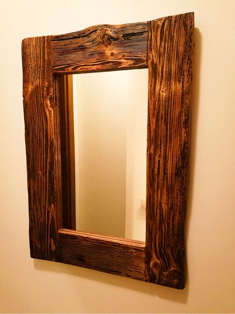 Puede incluir: Un espejo de madera r&uacute;stico con un acabado marr&oacute;n oscuro. El marco est&aacute; hecho de madera recuperada con un patr&oacute;n de veta de madera natural. El espejo es rectangular y tiene un dise&ntilde;o simple.