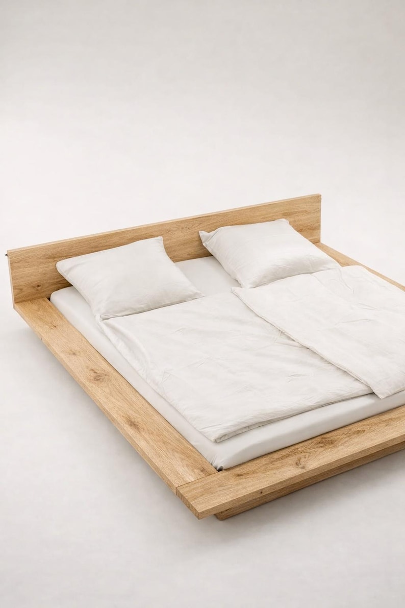 Puede incluir: Una moderna cama de madera con cabecero, con ropa de cama y almohadas blancas. El marco de la cama es de madera clara y tiene un dise&ntilde;o minimalista. La cama mide aproximadamente 200 cm de largo y 152 cm de ancho.