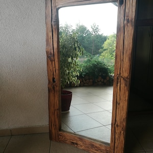 Puede incluir: Un espejo de madera r&uacute;stico con un marco rectangular. El marco est&aacute; hecho de madera recuperada con un acabado marr&oacute;n natural. El espejo refleja una vista de &aacute;rboles y un patio.