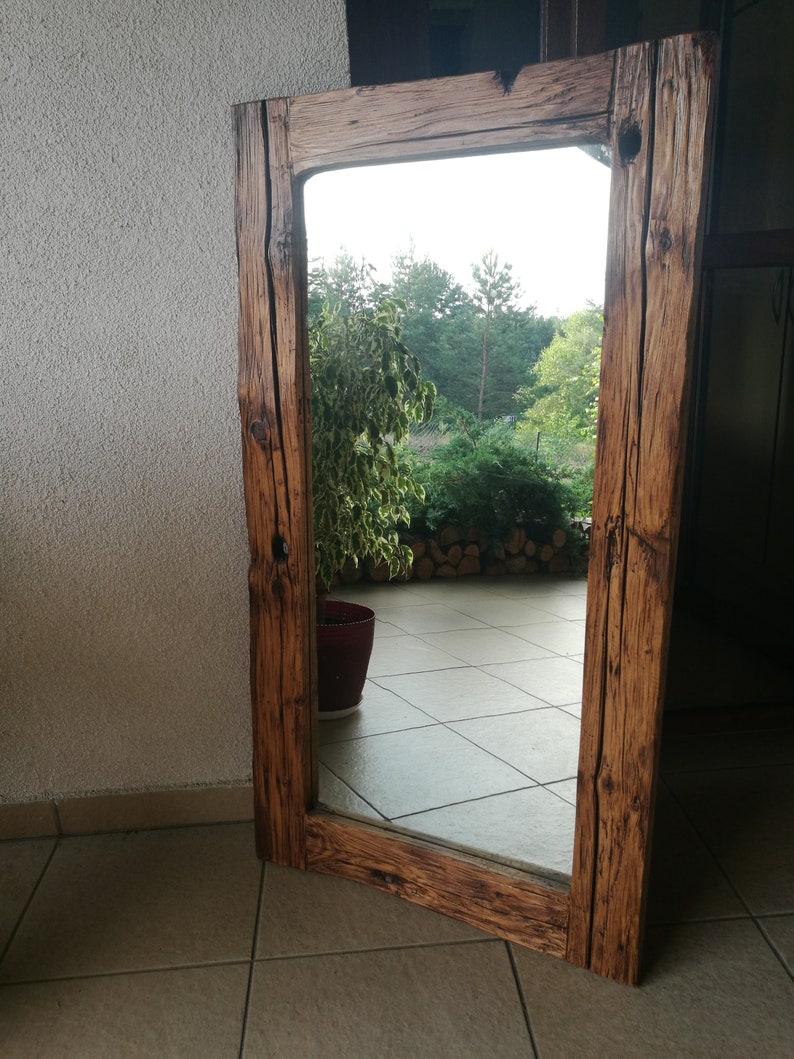 Puede incluir: Un espejo de madera r&uacute;stico con un marco rectangular. El marco est&aacute; hecho de madera recuperada con un acabado marr&oacute;n natural. El espejo refleja una vista de &aacute;rboles y un patio.