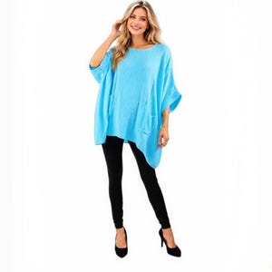 May include: A bright turquoise loose-fitting tunic top with short wide sleeves and an asymmetrical hemline paired with slim-fitting black leggings and black high-heeled shoes. The top features a round neckline and a relaxed, flowing silhouette.