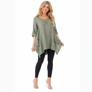 May include: An olive green tunic top with a lace-up neckline, three-quarter length sleeves, and an asymmetrical hemline, paired with solid black leggings and light-colored heeled sandals. The tunic features a loose, flowing fit and side pockets.