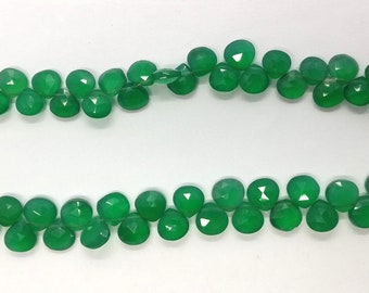 Puede incluir: Una hebra de cuentas de piedras preciosas verdes, cada cuenta está facetada y tiene una forma redondeada.