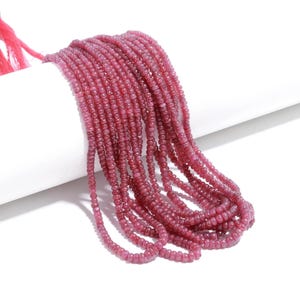 May include: A long strand of small, round, deep pink ruby beads arranged in multiple parallel rows. The beads have a smooth, polished texture and a consistent, vibrant magenta-pink colour, creating a dense, uniform appearance throughout the strand.