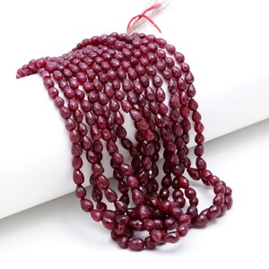 Peut inclure: Un brin de perles de rubis rouge foncé en forme de goutte. Les perles sont facettées et ont une finition polie.