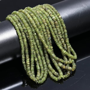 以下が含まれることがあります： 緑色の宝石ビーズの紐、おそらくペリドットで、緩く積み重ねられています。ビーズは小さく丸く、わずかにファセットが施されています。ビーズは明るい緑色で、わずかに輝いています。