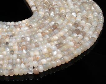May include: A strand of moonstone beads. The beads are a mix of white, cream, and light brown colors. The beads are small, rounded, and strung together, creating a flowing, organic shape. The beads have a subtle sheen.