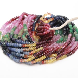 Könnte beinhalten: Eine Strähne aus bunten Edelsteinperlen, darunter blau, grün, rosa, rot und gelb. Die Perlen sind facettiert und haben eine polierte Oberfläche.