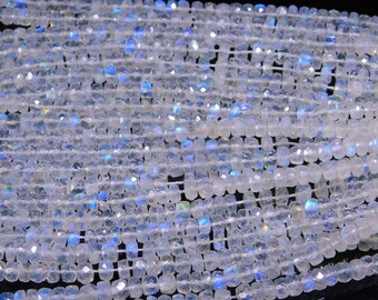 May include: A strand of white iridescent moonstone beads. The beads are faceted and have a square shape. The beads are strung on a white thread.
