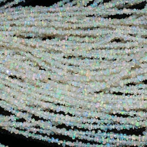 May include: A strand of white opal chip beads. The beads are small and irregular in shape, with a slight iridescent sheen.