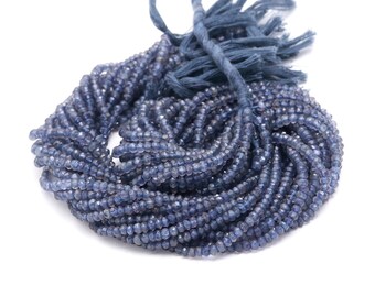 May include: A strand of blue gemstone beads, likely kyanite, with a tassel at the end. The beads are small and round, and the strand is coiled up.