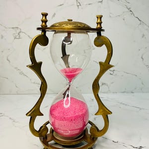 Reloj de arena decorativo de latón con arena rosa para mesa, ideal para el hogar o la oficina. Regalo perfecto.