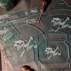 May include: A set of clear plastic stencils for leather crafting. The stencils feature the text "Hook n Hose" and various shapes and sizes for creating straps and other leather goods.