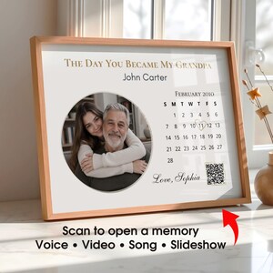 Puede incluir: Un marco con un marco de madera clara. La impresión presenta una foto de un hombre y una mujer, un calendario de febrero de 2010 y el texto "THE DAY YOU BECAME MY GRANDPA" y "Love, Sophia". La impresión también incluye un código QR.