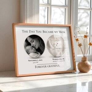 Puede incluir: Una impresión enmarcada con un marco de madera clara. La impresión presenta una foto en blanco y negro de una madre y un bebé, un gráfico de globo y el texto "THE DAY YOU BECAME MY MOM". El texto adicional incluye la fecha, la hora y la ubicación.