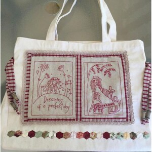 Puede incluir: Una bolsa de lona blanca con detalles de tela de cuadros rojos y blancos. La bolsa presenta dos escenas bordadas con el texto "Dreaming of a perfect day".
