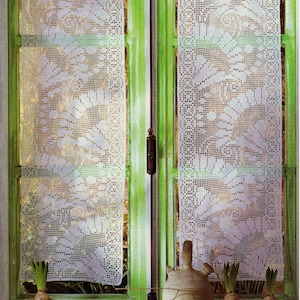 May include: Two white crocheted curtains with a floral design hang in a window with green trim. The window is decorated with potted hyacinths and a brown ceramic jug.