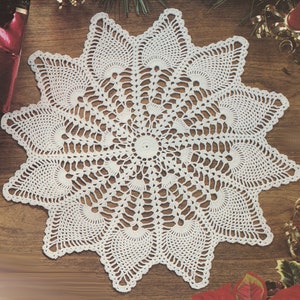 May include: A white crocheted doily with a starburst design. The doily is made with delicate stitches and has a lacy appearance.