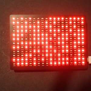 K&ouml;nnte beinhalten: Ein rotes LED-Matrix-Display mit einem angeschlossenen USB-Kabel. Das Display befindet sich auf einer dunklen Oberfl&auml;che.