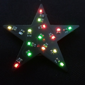 以下が含まれることがあります： 赤、緑、黄色のLEDライトが付いた星型の回路基板。基板には「R1」、「R2」、「R3」、「R4」、「R5」、「R6」、「R7」、「R8」、「R9」、「R10」、「R11」、「R12」、「R13」、「R14」、「R15」、「R16」の文字が書かれています。