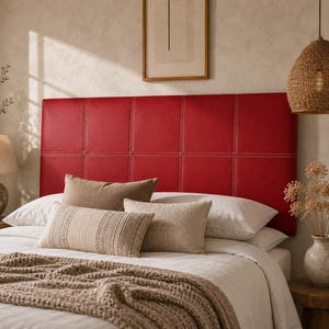 Peut inclure: Une tête de lit rectangulaire rouge rembourrée présentant un motif en grille de panneaux carrés avec des coutures blanches visibles le long des coutures. La tête de lit est placée derrière un lit habillé de linge blanc avec des coussins beiges.