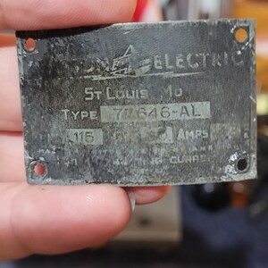 Puede incluir: Una placa met&aacute;lica desgastada con el texto "Wagner Electric" y "St. Louis Mo." La placa tiene el tipo "77646-AL" y "115 AMPS" impresos. Hay cuatro agujeros en las esquinas.
