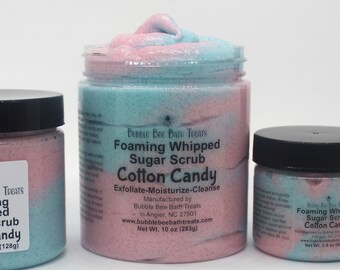 May include: Three jars of cotton candy-scented foaming whipped sugar scrub. The jars are labeled "Cotton Candy" and have a pink and blue swirl pattern. The largest jar contains 10 oz (283g).