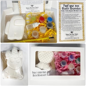 Puede incluir: Un kit de bombas de baño DIY con bombas de baño con forma de personaje de Among Us, unicornio y sirena. El kit incluye botes de pintura, alcohol y un pincel. La caja tiene el texto "Paint your own Bath Bomb Kit!"