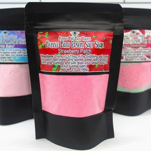 May include: Three black pouches of Bubble Bee Bath Treats Epsom Salt Soak. The center pouch is labeled "Strawberry Patch" with a pink powder inside. The label includes instructions and a net weight of 3.5 oz (99g).
