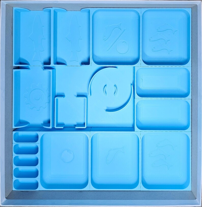 May include: A light blue organizer with multiple compartments for storing small items. The compartments have various shapes and sizes, including circles, squares, and rectangles. The organizer is made of plastic and has a smooth surface.