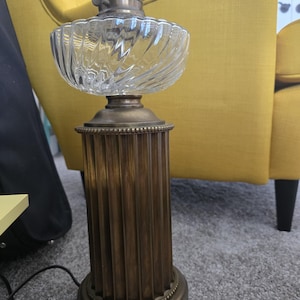 May include: A vintage brass lamp with a clear glass shade. The lamp has a fluted column base and a decorative top.