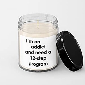 May include: A clear glass candle jar with a black lid. The candle is white and has a label that reads "I'm an addict and need a 12-step program."