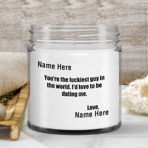 May include: A white candle jar with a black label that reads "Name Here You're the luckiest guy in the world. I'd love to be dating me. Love, Name Here".