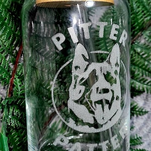 May include: A clear glass jar with a bamboo lid and a straw. The jar is etched with the words "Pitter Patter" and a dog's head.