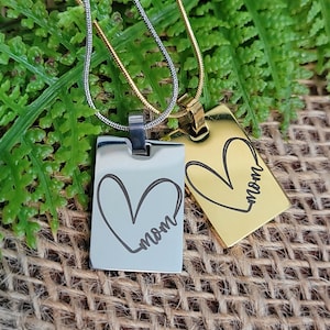 May include: Two silver and gold necklaces with rectangular pendants. Each pendant has a heart with the word "mom" inscribed inside.