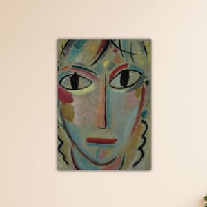 Puede incluir: Pintura de retrato abstracto que presenta un rostro con ojos grandes y oscuros y una nariz larga. La obra de arte utiliza una paleta de azules, rosas y amarillos, con contornos negros. La pintura está montada en una pared.