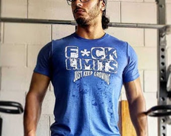 Puede incluir: Un hombre con una camiseta azul con el texto "F*CK LIMITS JUST KEEP GROWING" en blanco. Lleva una boina negra y gafas.