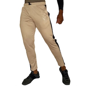 May include: Beige sweatpants with black side stripes and a silver logo on the left leg.