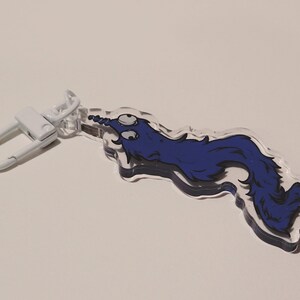 May include: A blue and white cartoon worm keychain with a white metal clasp. The worm has two large eyes and a curled tail.