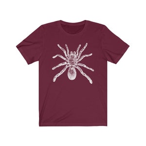 May include: A maroon t-shirt with a white graphic of a spider.
