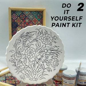 May include: A white ceramic plate with a black and white floral design. The plate is part of a paint-your-own pottery kit. The kit includes paint and brushes. The kit is labeled "Do It Yourself Paint Kit".