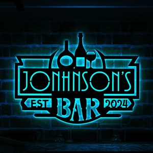 May include: A blue neon sign with the text "JOHNSON'S EST BAR 2024" and images of bottles and a wine glass. The sign is mounted on a brick wall and is controlled by a remote control.